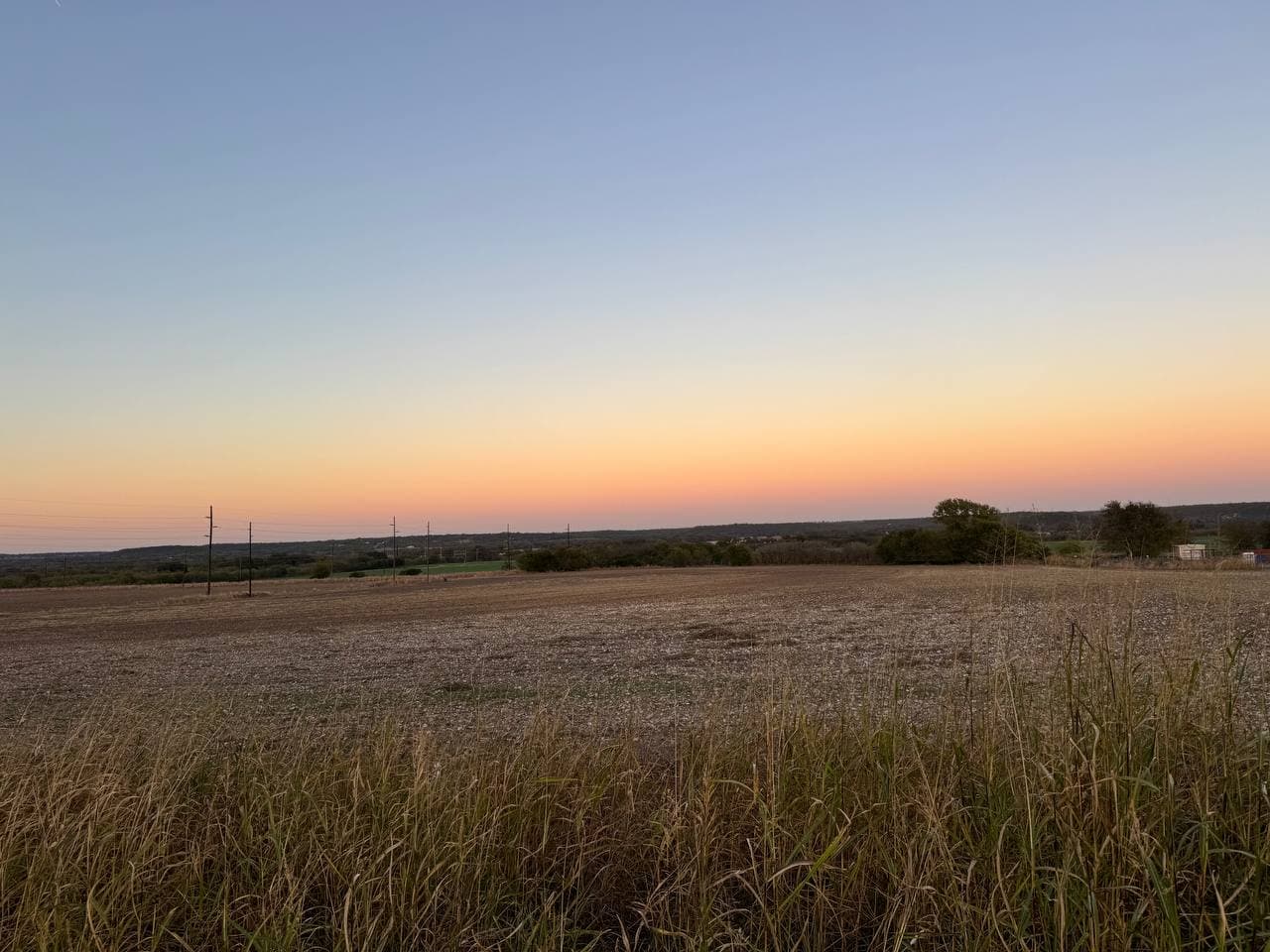 Site at sunset showing flat terrain and power lines